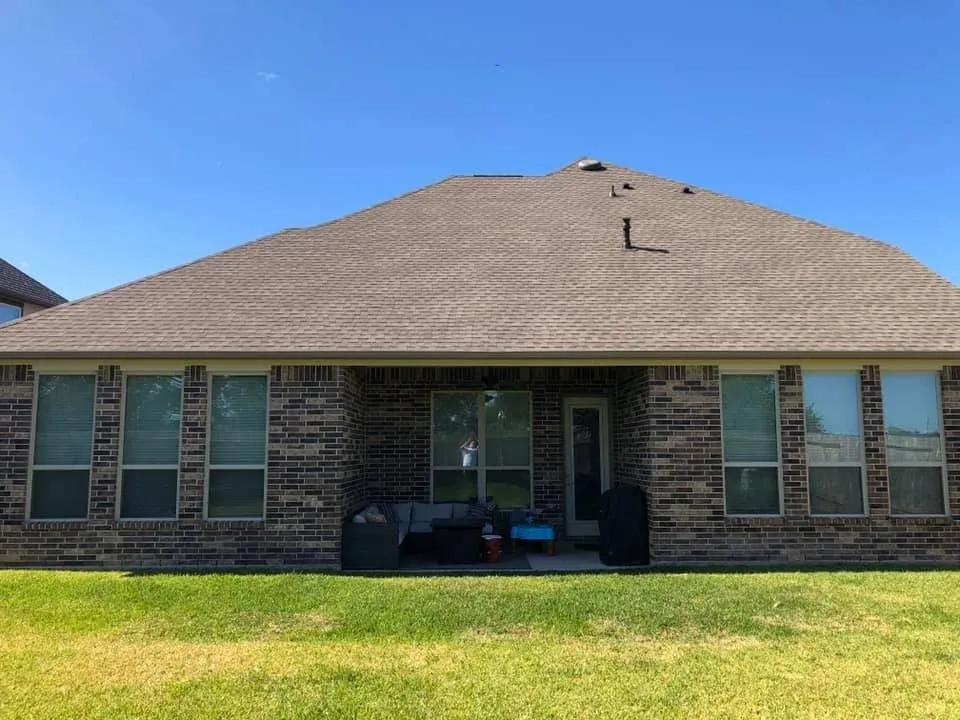 Rear exterior of brick custom home with covered patio