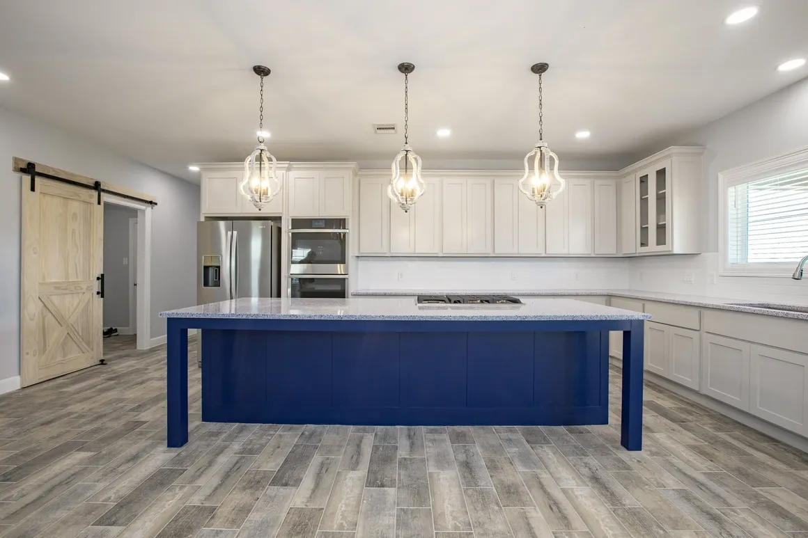 White kitchen with bold blue island and pendant lighting