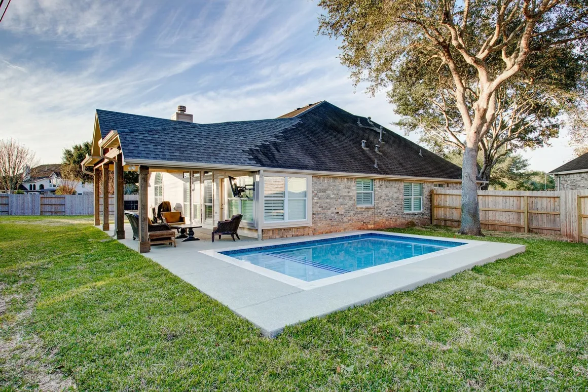 Backyard pool and patio area behind a custom Hawkeye Construction home
