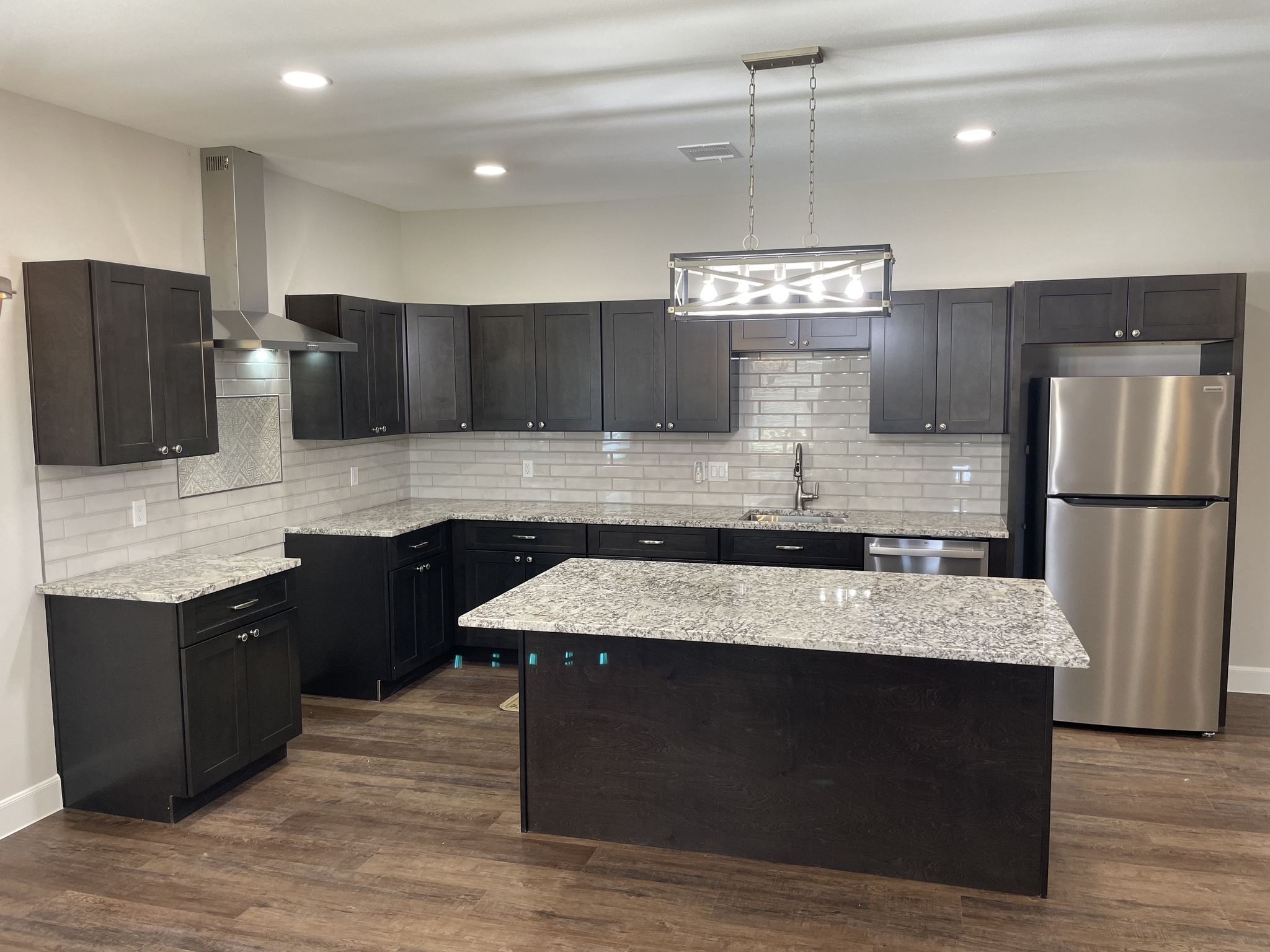 Modern kitchen with black cabinets, large island, and pendant lighting