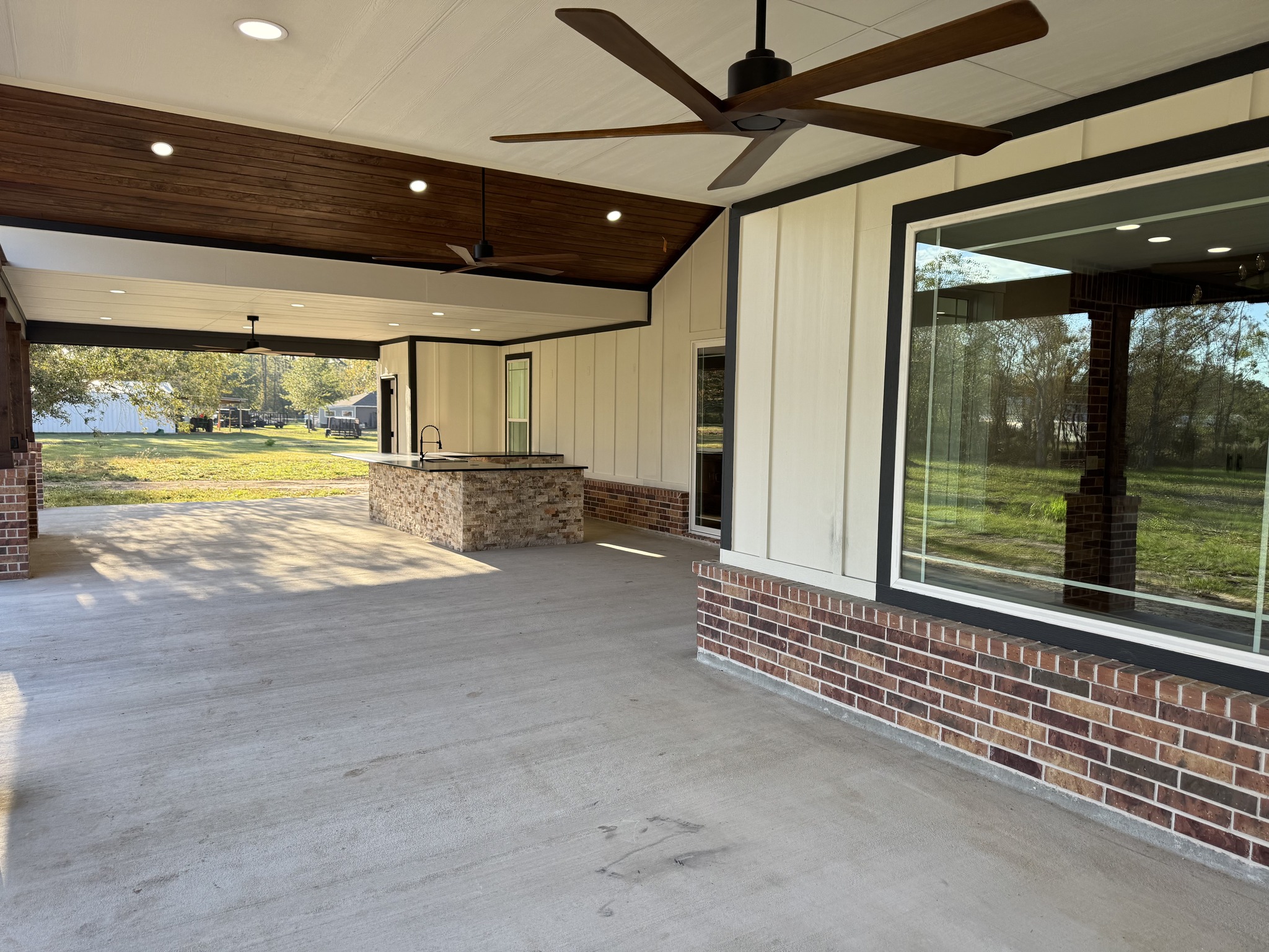 Covered patio with wood ceiling, brick fireplace, and sliding glass doors