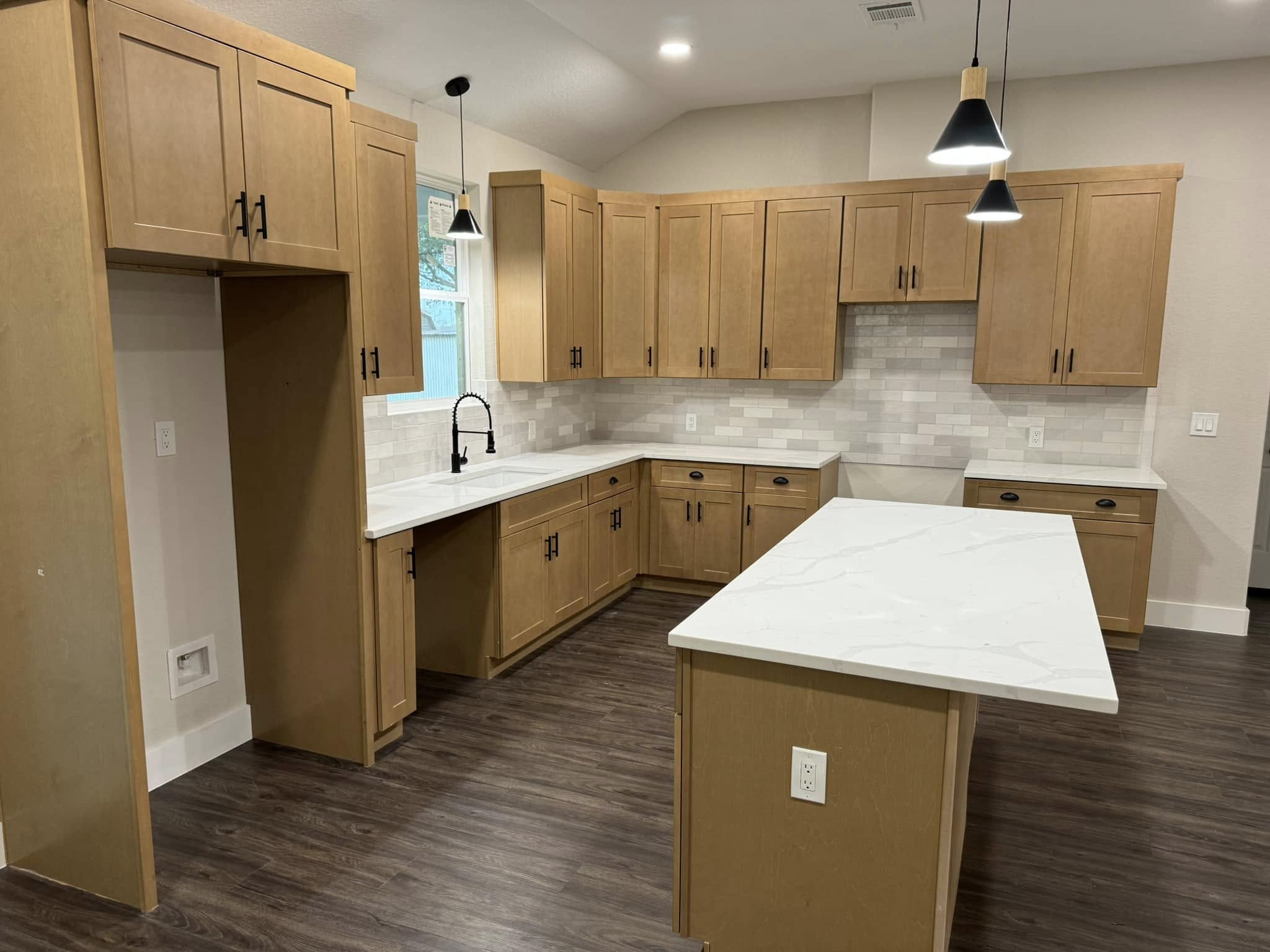 Warm-toned kitchen with island, pendant lights, and tile backsplash