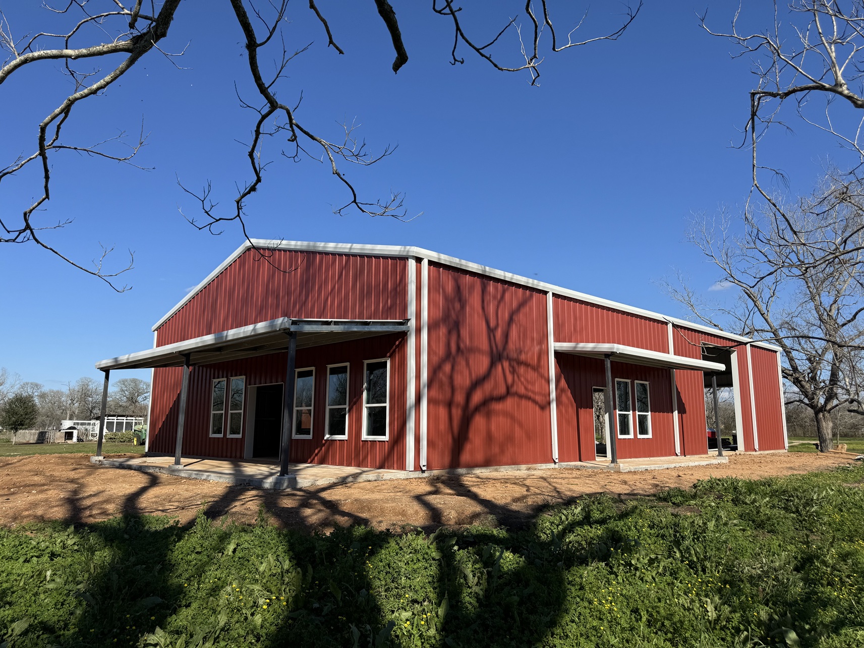 Red metal building with front porch and landscaping