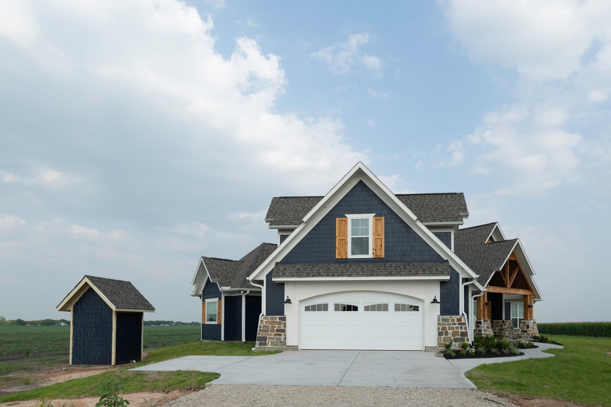 Two-story home with white garage door, stone accents and shed.