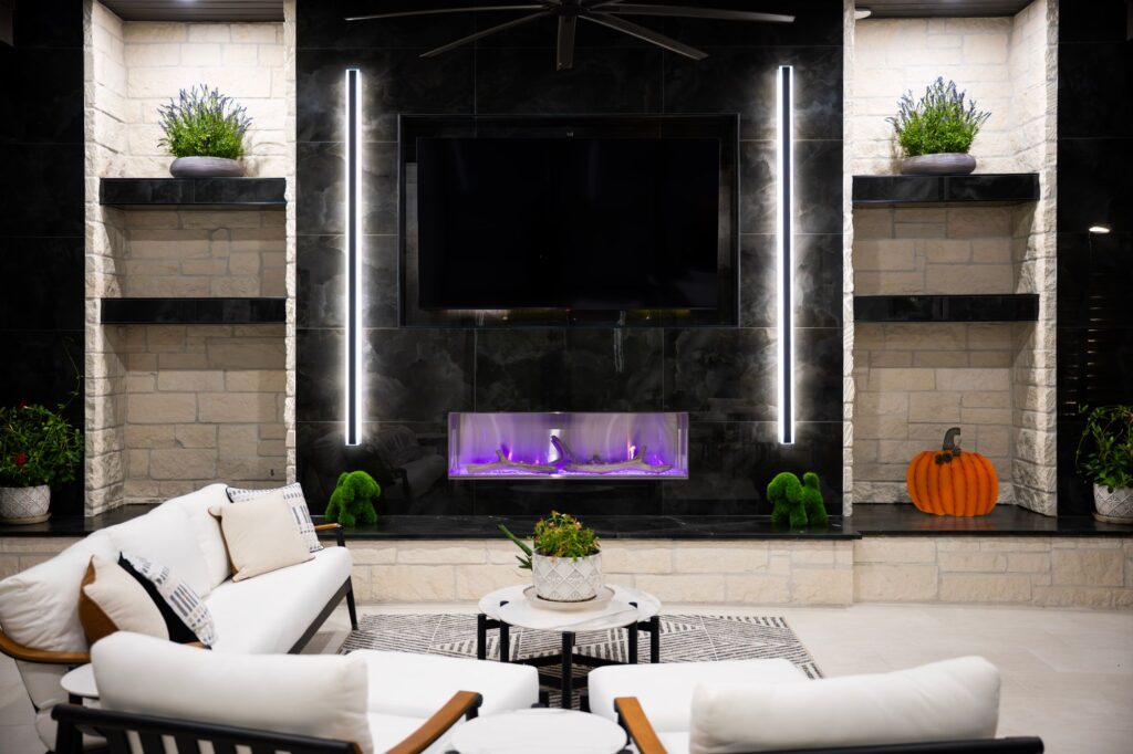Modern covered patio with a marble fireplace wall and TV in Sienna, Missouri City.