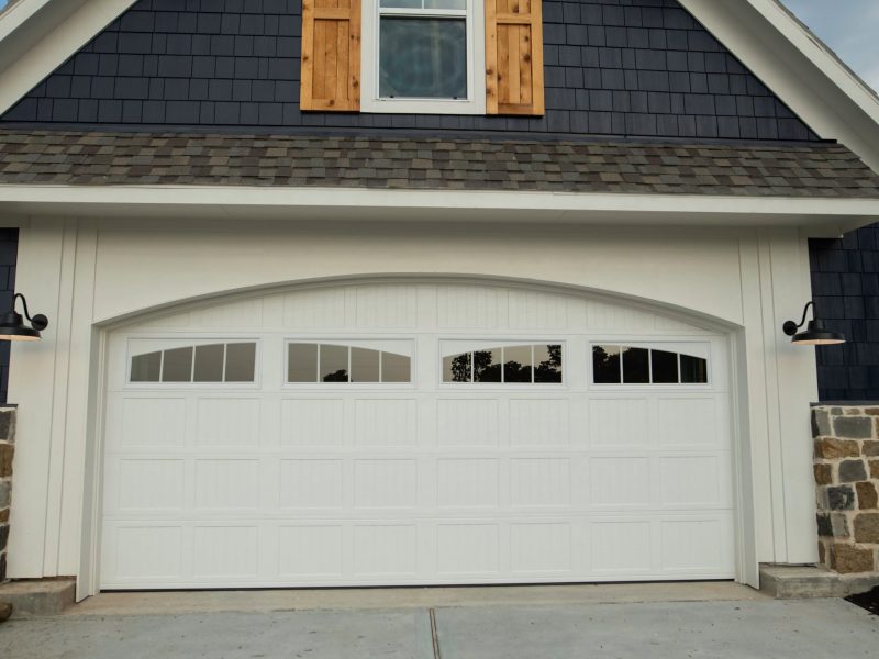 Carriage-style garage door with cedar shutters and stone.