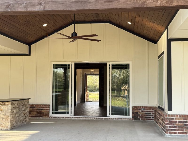 Covered patio with wood ceiling and sliding doors.