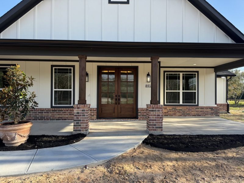 Front porch with wood double doors, cedar posts and brick bases.