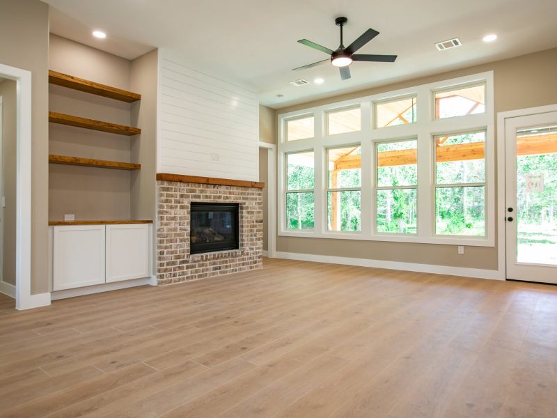 Living room with brick fireplace, shiplap chimney and wall of windows.