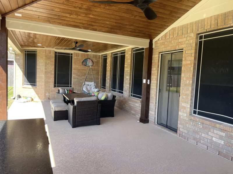 Long covered patio with wood ceiling and seating.