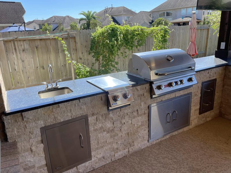 Outdoor kitchen with built-in grill, sink and stacked stone.