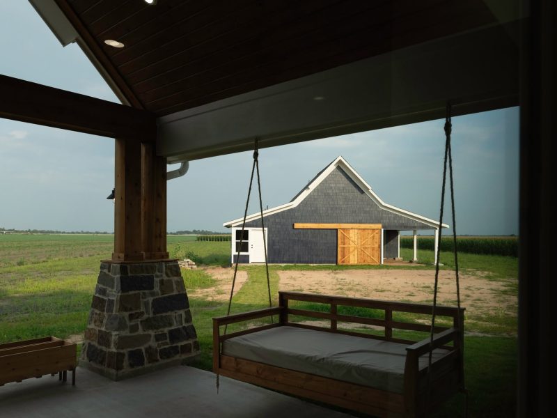 Porch swing on covered porch looking out to barn.
