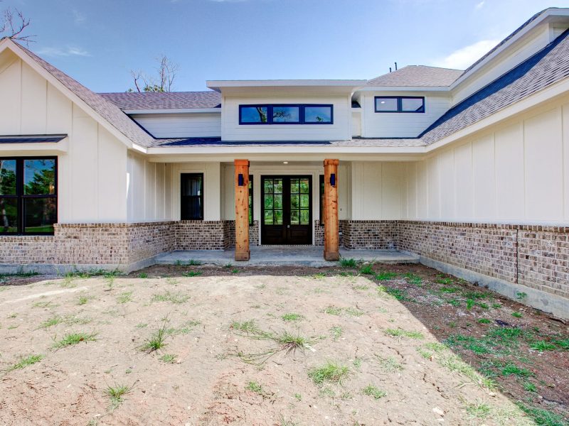 White farmhouse front with brick wainscot and cedar porch posts.