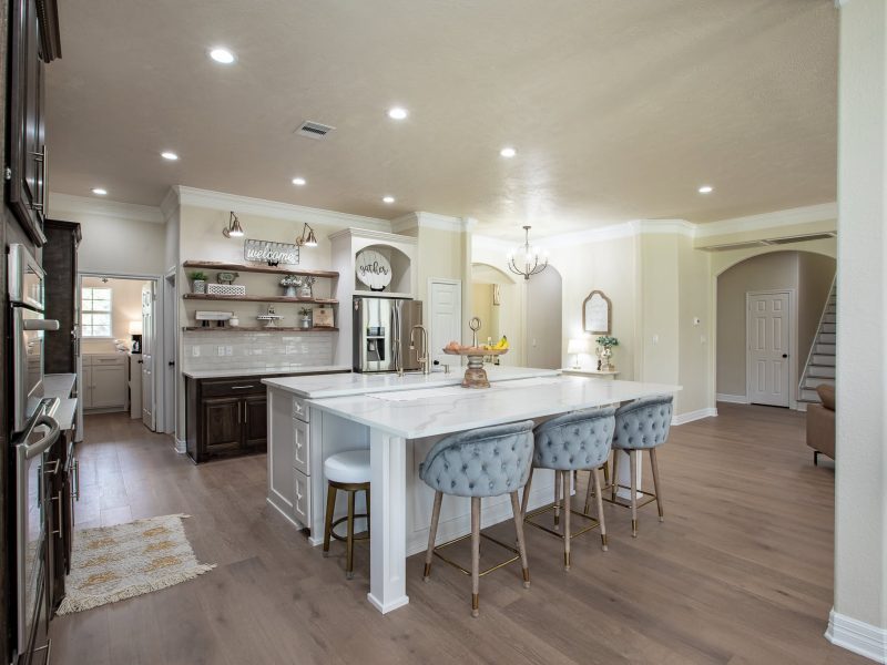 White island with tufted stools and open shelving.