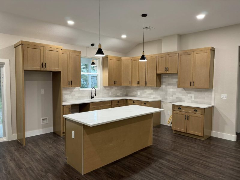 Wood cabinet kitchen with island and black pendants.