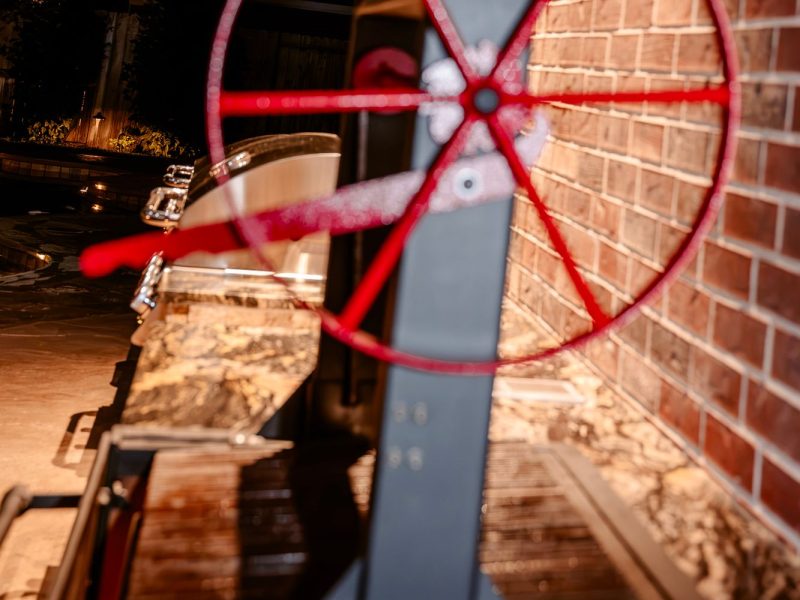 Red wheel of a Santa Maria grill in the outdoor kitchen pavilion.